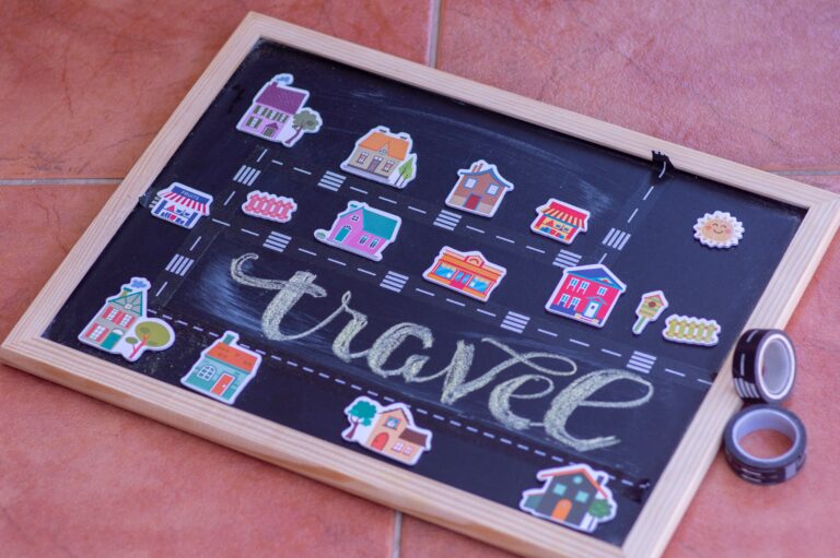 Blackboard with neighborhood pictures and the word travel written with chalk.