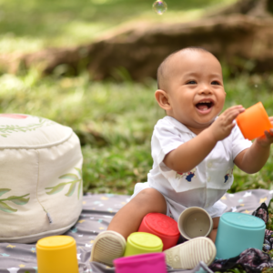 baby playing outside with cups